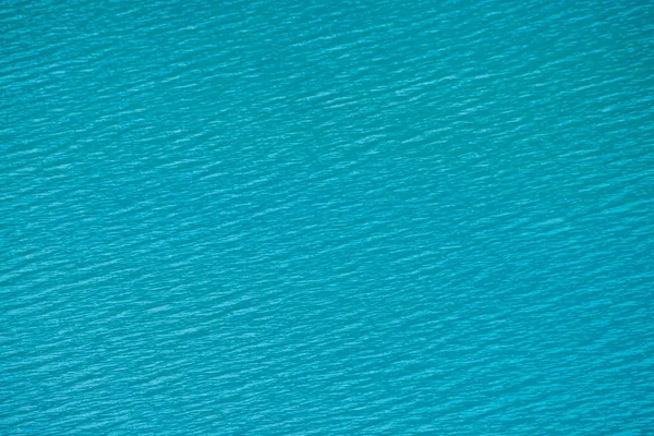 Amazing textured background of calm azure clean water surface. Sunshine in mountain lake close up. Beautiful ripples on shiny water in sunny day. Wonderful relax texture.