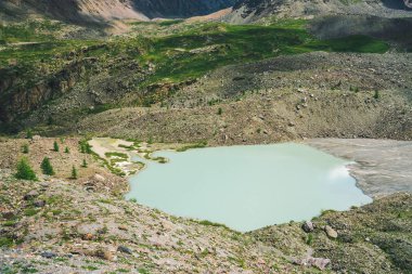 Yaylalar vadisinde dağ gölü. Bitki örtüsü olan dev dağ yamacı. İnanılmaz kayalar. Harika dağlar. Pürüzsüz su yüzeyi. Görkemli doğanın atmosferik kozmik manzarası.