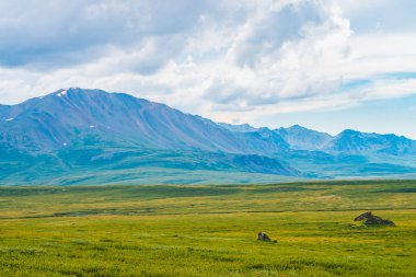 Bulutlu gökyüzü altında dev dağların muhteşem görünümü. Bulutlu havalarda büyük bir dağ sırası. Harika vahşi manzara. Görkemli doğanın atmosferik dramatik yayla manzara. Doğal dağ manzarası.