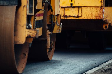 Sarı bir asfalt kompaktör yolu hizalar. Yeni asfalt döşeme.