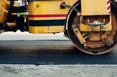 Sarı bir asfalt kompaktör yolu hizalar. Yeni asfalt döşeme.