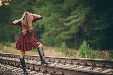 Güzel üzgün kız saçtan yüz saklıyor. Demiryolunda ormanda bordo elbiseli huysuz kadın. Şafakta demiryolunda depresif yalnız bir kız. Sonbaharda kıvırcık doğal saçgüneş. Kötü ruh hali. Rahatsız kız.
