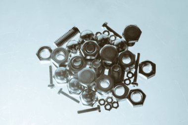 Cıvata ve somunlardan art monokrom arka plan mavi arka ışıkta kapanır. Bir avuç bağlantı elemanının makro fotoğrafçılığı.