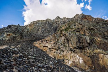 Tepenin üstünde dev bir bulut. Bitki örtüsü ile alışılmadık kayalık dağ. Mavi bulutlu gökyüzü altında Amazing dağ aralığı. Harika kayalar. Yaylaların görkemli doğasının atmosferik manzarası.