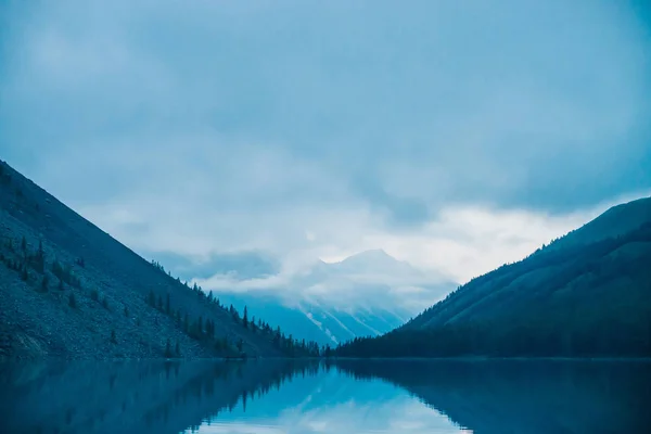 Silhuetas Incríveis Montanhas Nuvens Baixas Refletidas Lago Montanha Lindas Ondulações — Fotografia de Stock