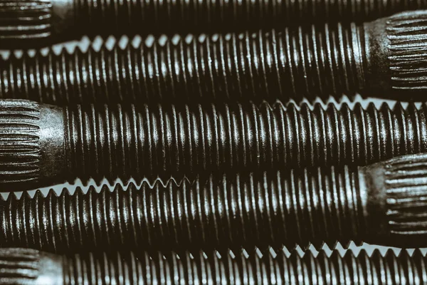 Monochrome background from automotive bolts close up.