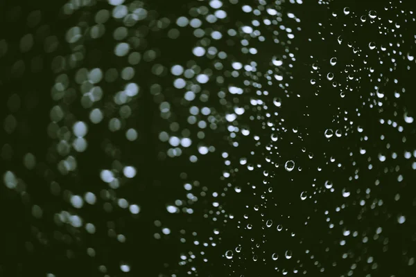 雨の滴と汚れた窓ガラス ボケの雨滴と大気緑の背景 液滴と汚れがクローズアップ コピースペースを持つマクロ内の詳細な透明テクスチャ — ストック写真