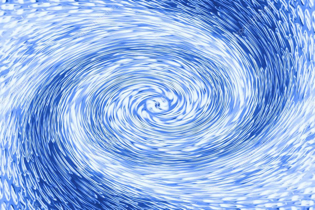 Space matter revolves around a spiral wormhole of cobalt color. Fantastic background image of asymmetric vortex tunnel in center of shot in blue.