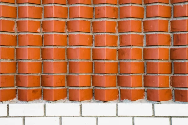 Red brick wall from diagonally angular bricks. Geometric background image from brown horn bricks. Compound with smooth white brickwork at bottom.