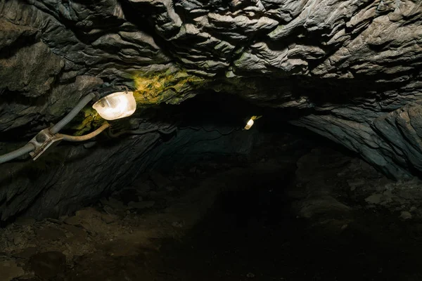 Beautiful cave. View from inside dark dungeon. Textured walls of cave. Background image of underground tunnel. Dampness inside cave. Lighting inside cave for excursions.