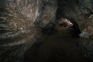 Güzel bir mağara. Karanlık zindandan manzara. Mağaranın dokulu duvarları. Yeraltının arka plan görüntüsü. Mağaranın içinde nem var. Tünelin sonundaki ışık.