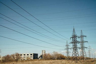 Mavi gökyüzü arka planda yüksek voltaj telleri ile mesaj grubu. Kopyalama alanı ile gökyüzünde sütunlar ve tellerin arka plan görüntüsü. Arka planda eski bina.