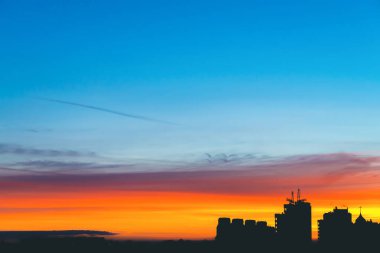 Harika varirenkli canlı şafak ile Cityscape. Şehir binalarının karanlık siluetleri üzerinde inanılmaz dramatik çok renkli bulutlu gökyüzü. Gün doğumunun atmosferik arka planı. Turuncu güneş ışığı. Kopyalama alanı.