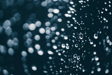 Yağmur damlalarıyla kirli pencere camı. Bokeh yağmur damlaları ile atmosferik mavi arka plan. Damlacıklar ve lekeler kapanır. Kopyalama alanı ile makroda ayrıntılı saydam doku. Yağmurlu hava.