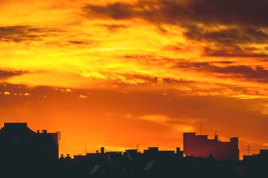 Cityscape canlı ateşli şafak ile. İnanılmaz sıcak dramatik bulutlu gökyüzü karanlık siluetleri şehir binaların yukarıda. Turuncu güneş ışığı. Gündoğumu bulutlu havalarda atmosferik arka plan. Kopya alanı.