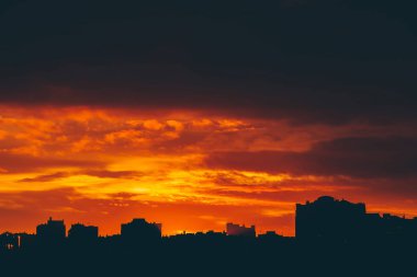 Cityscape canlı ateşli şafak ile. İnanılmaz sıcak dramatik bulutlu gökyüzü karanlık siluetleri şehir binaların yukarıda. Turuncu güneş ışığı. Gündoğumu bulutlu havalarda atmosferik arka plan. Kopya alanı.