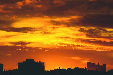 Cityscape canlı ateşli şafak ile. İnanılmaz sıcak dramatik bulutlu gökyüzü karanlık siluetleri şehir binaların yukarıda. Turuncu güneş ışığı. Gündoğumu bulutlu havalarda atmosferik arka plan. Kopya alanı.