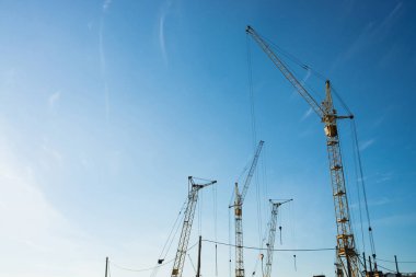 Mavi gökyüzüne karşı büyük kule vinçler. Kopyalama alanı ile yakın çekim inşaat ekipmanları arka plan görüntüsü. Şehrin inşası.