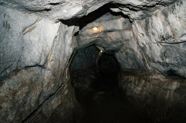 Güzel bir mağara. Karanlık zindandan manzara. Mağaranın dokulu duvarları. Yeraltı tünelinin arka plan görüntüsü. Mağaranın içinde nem var. Geziler için mağara içinde Aydınlatma.