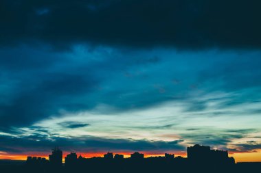 Harika varirenkli canlı şafak ile Cityscape. Şehir binalarının karanlık siluetleri üzerinde inanılmaz dramatik çok renkli bulutlu gökyüzü. Bulutlu havalarda gün doğumunun atmosferik arka planı. Kopyalama alanı.