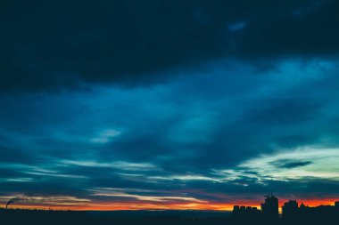 Harika varirenkli canlı şafak ile Cityscape. Şehir binalarının karanlık siluetleri üzerinde inanılmaz dramatik çok renkli bulutlu gökyüzü. Bulutlu havalarda gün doğumunun atmosferik arka planı. Kopyalama alanı.