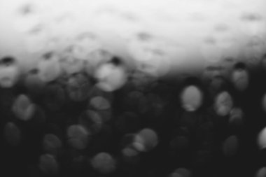 Yağmur damlalarıyla kirli pencere camı. Bokeh yağmur damlaları ile atmosferik tek renkli koyu arka plan. Damlacıklar ve lekeler kapanır. Makroda ayrıntılı saydam doku. Kopya alanı. Yağmurlu hava.