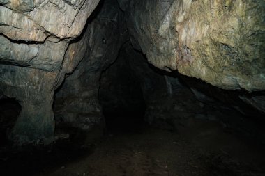 Güzel bir mağara. Karanlık zindandan manzara. Mağaranın dokulu duvarları. Yeraltı tünelinin arka plan görüntüsü. Mağaranın içinde nem var. Tünelin sonundaki ışık.