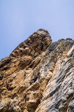 Bulutlu gökyüzü yakın çekim altında büyük dağ uçurumu. Bitki örtüsü ile güzel kayalık gri dokulu arka plan. Görkemli doğa.