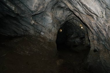 Güzel bir mağara. Karanlık zindandan manzara. Mağaranın dokulu duvarları. Yeraltı tünelinin arka plan görüntüsü. Mağaranın içinde nem var. Geziler için mağara içinde Aydınlatma.