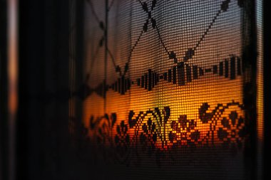 Desenli perde ile pencereden Harika canlı şafak. Tül doku siluetleri arkasında Inanılmaz sıcak gökyüzü. Turuncu güneş ışığı. Rahatlık gün doğumu ile renkli arka plan dokulu. Kopyalama alanı.