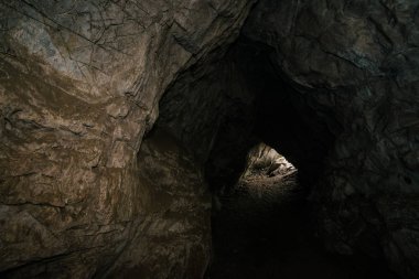 Güzel bir mağara. Karanlık zindandan manzara. Mağaranın dokulu duvarları. Yeraltının arka plan görüntüsü. Mağaranın içinde nem var. Tünelin sonundaki ışık.