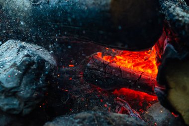 Yanan kütükler canlı ateşte yandı. Kamp ateşi turuncu alev ile atmosferik arka plan. Kopya alanı ile içeriden şenlik ateşi hayal edilemez ayrıntılı görüntü. Duman ve kül kasırgası yakın.