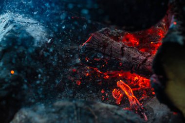 Yanan kütükler canlı ateşte yandı. Kamp ateşi turuncu alev ile atmosferik arka plan. Kopya alanı ile içeriden şenlik ateşi hayal edilemez ayrıntılı görüntü. Duman ve kül kasırgası yakın.