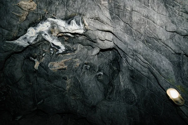 Beautiful cave. View from inside dark dungeon. Textured walls of cave. Background image of underground tunnel. Dampness inside cave. Lighting inside cave for excursions.