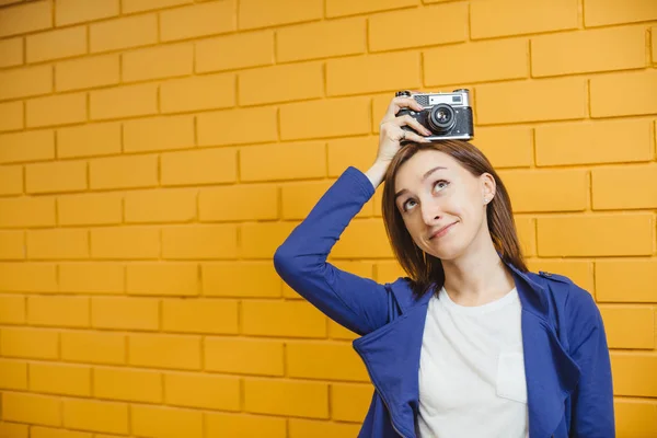 背景に黄色のレンガの壁にレトロな金属フィルムカメラを持つ美しい狂気の女の子 — ストック写真