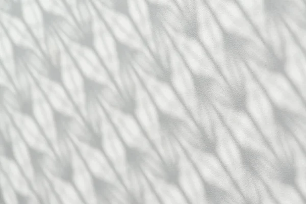 Shadow from patterned tulle falls on white wooden surface. Patterned picture on wooden white background.