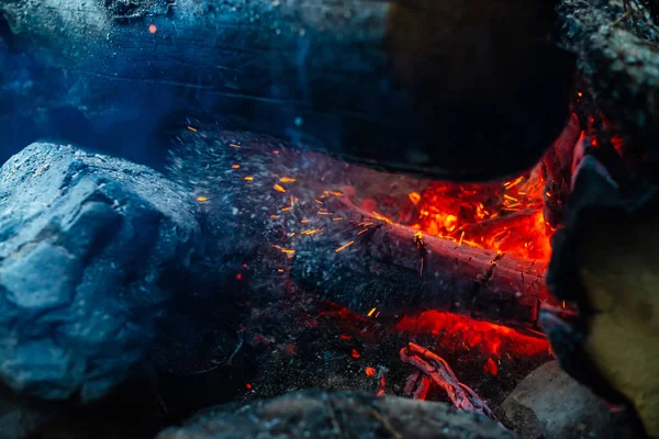 鮮やかな火の中で焼かれた解体されたログを閉じます キャンプファイアの炎と大気中の背景 コピースペースと内側からたき火の想像を絶する詳細なイメージ 煙と輝くメンバーの渦 — ストック写真