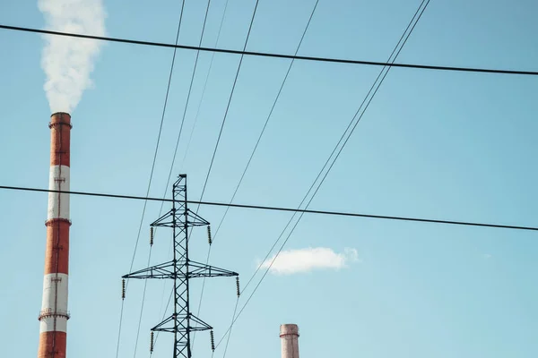 Yüksek kırmızı ve beyaz çizgili tüp berrak mavi gökyüzüne beyaz duman sağlar. Elektrik direği ve güç telleri arka plan üzerinde boru üzerinde küçük bulut. Termik santral fotokopi alanı ile yakın çekim.