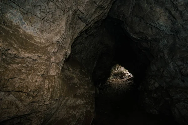 美しい洞窟だ暗いダンジョンの中からの眺め 洞窟のテクスチャードの壁 地下の背景画像 洞窟内の湿気 トンネルの終点の光 — ストック写真