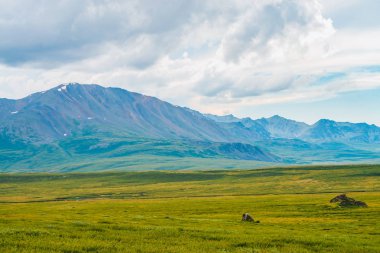 Bulutlu gökyüzü altında dev dağların muhteşem görünümü. Bulutlu havalarda büyük bir dağ sırası. Harika vahşi manzara. Görkemli doğanın atmosferik dramatik yayla manzara. Doğal dağ manzarası.