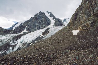 Dağ lık dağda kar. Bulutlu gökyüzü altında atmosferik karlı sırt. Bulutlu havalarda alışılmadık dev kayalar. Dağlarda yükseke tırmanın. Yaylaların görkemli doğasının inanılmaz minimalist manzarası.