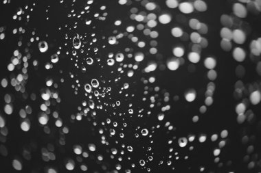 Yağmur damlalarıyla kirli pencere camı. Bokeh yağmur damlaları ile atmosferik tek renkli koyu arka plan. Damlacıklar ve lekeler kapanır. Makroda ayrıntılı saydam doku. Kopya alanı. Yağmurlu hava.