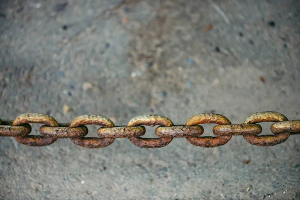 stock image Old oxidized rusty chain hanging over asphalt close up with copy space. Conceptual background with thick links of strong chain. Artwork.