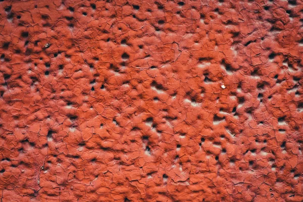 Side of building is painted red. Detailed imperfect texture of aerated foam block with holes close-up. Background of construction from foamed material in macro with copy space. Decorative facing.