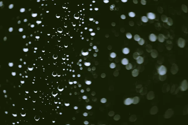 雨の滴と汚れた窓ガラス ボケの雨滴と大気緑の背景 液滴と汚れがクローズアップ コピースペースを持つマクロ内の詳細な透明テクスチャ — ストック写真