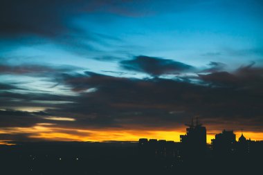 Harika varirenkli canlı şafak ile Cityscape. Şehir binalarının karanlık siluetleri üzerinde Inanılmaz dramatik mavi bulutlu gökyüzü. Bulutlu havalarda turuncu gündoğumu atmosferik arka plan. Kopyalama alanı.