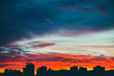 Harika varirenkli canlı şafak ile Cityscape. Şehir binalarının karanlık siluetleri üzerinde inanılmaz dramatik çok renkli bulutlu gökyüzü. Bulutlu havalarda gün doğumunun atmosferik arka planı. Kopyalama alanı.
