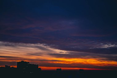 Harika varirenkli ateşli şafak ile Cityscape. İnanılmaz dramatik çok renkli bulutlu gökyüzü. Şehir binası çatılarının karanlık siluetleri. Bulutlu havalarda gün doğumunun atmosferik arka planı. Kopyalama alanı.