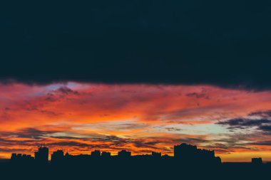 Harika varirenkli canlı şafak ile Cityscape. Şehir binalarının karanlık siluetleri üzerinde inanılmaz dramatik çok renkli bulutlu gökyüzü. Bulutlu havalarda gün doğumunun atmosferik arka planı. Kopyalama alanı.
