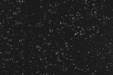 Yağmur damlalarıyla kirli pencere camı. Yağmur damlaları ile atmosferik tek renkli koyu arka plan. Damlacıklar ve lekeler kapanır. Kopyalama alanı ile makroda ayrıntılı saydam doku. Gece yağmurlu hava.